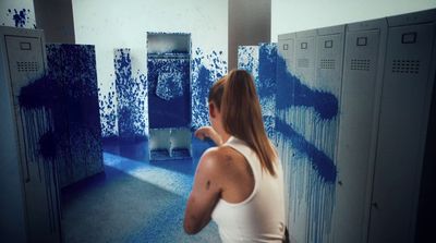 a woman in a white tank top painting a wall