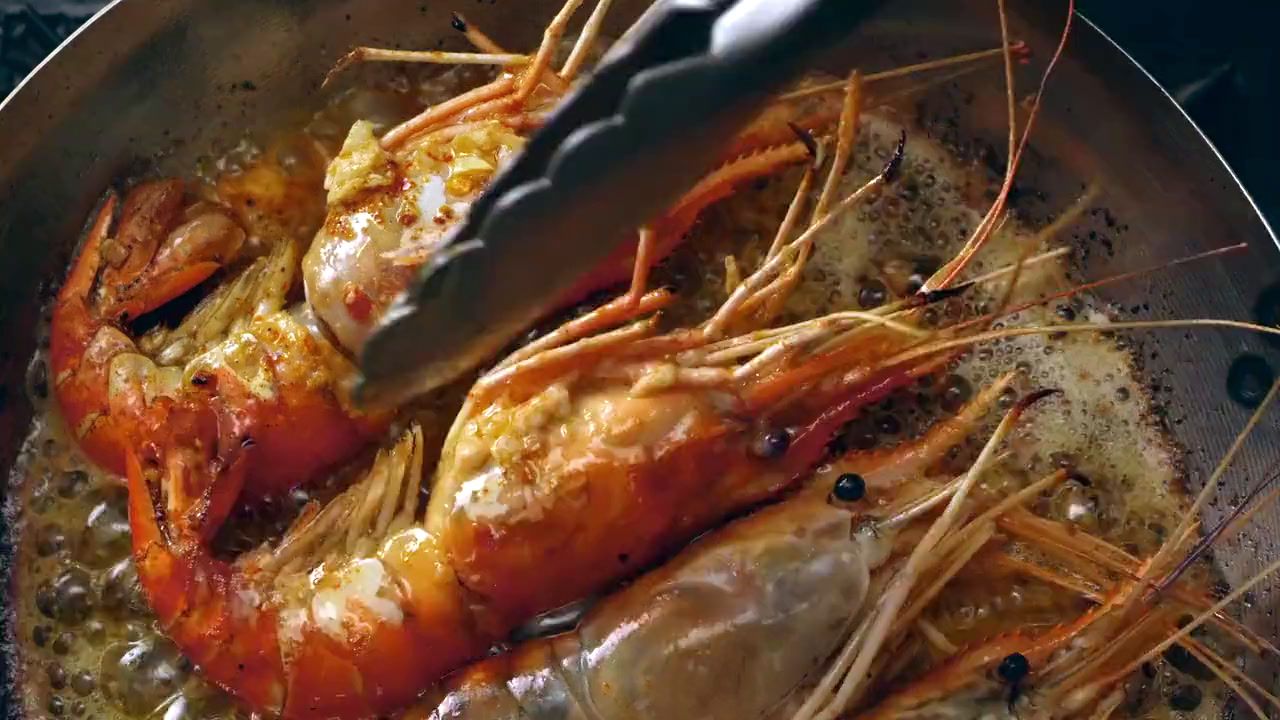 a pan filled with cooked shrimp on top of a stove