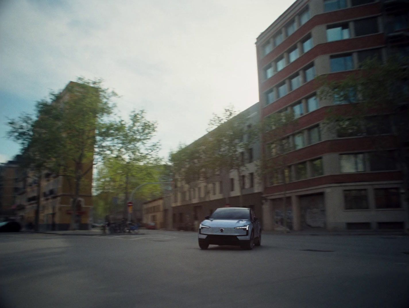 a silver car driving down a street next to tall buildings