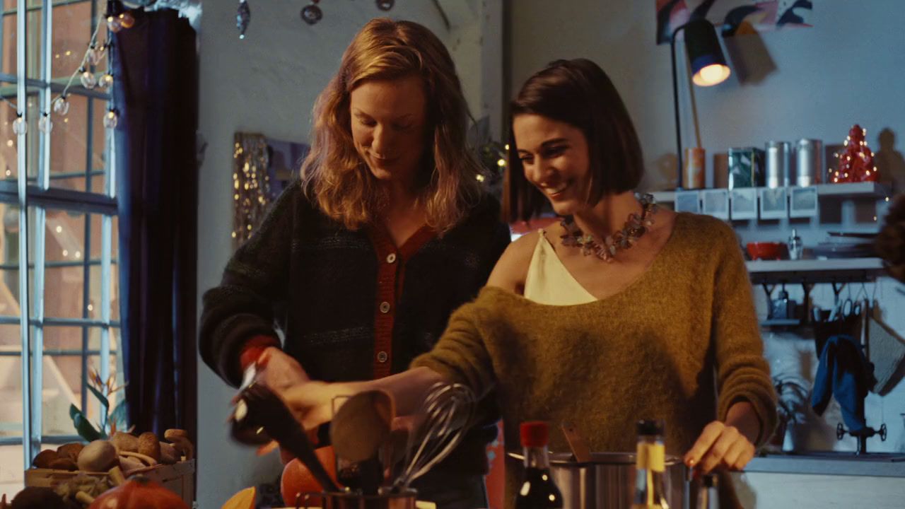 a couple of women standing next to each other in a kitchen