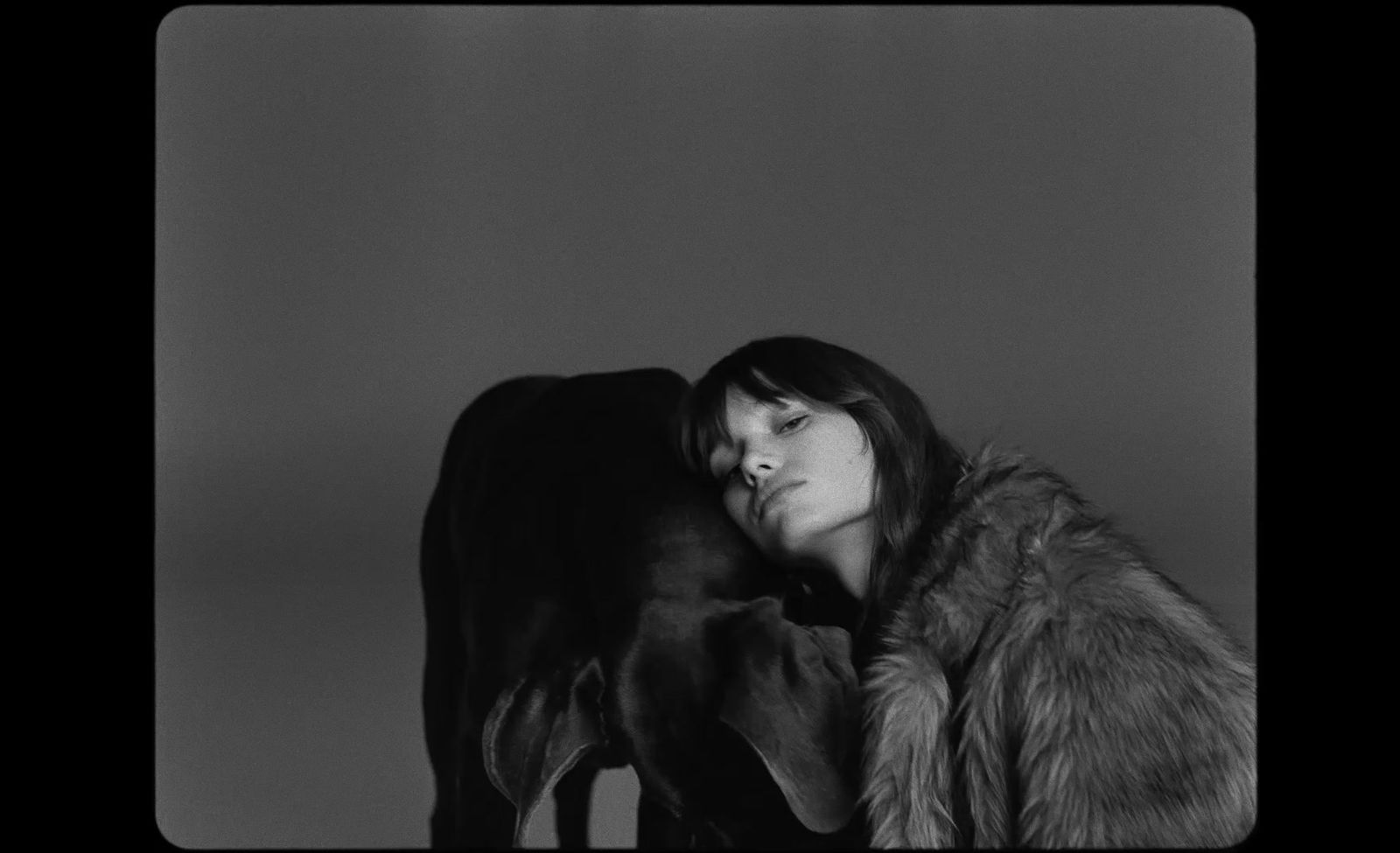 a black and white photo of a woman and a cow