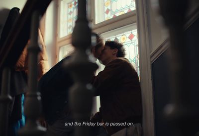 a man and woman kissing in front of a stained glass window