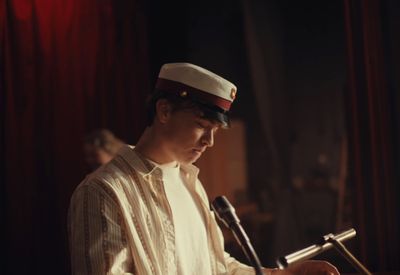 a man in a sailor's hat sitting in front of a microphone