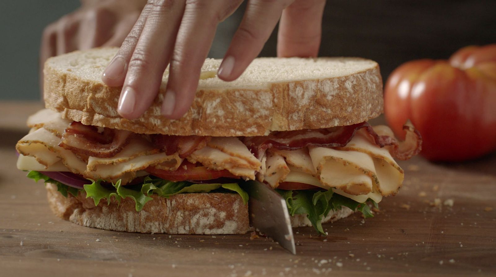 a person cutting a sandwich with a knife