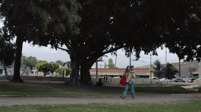 a woman walking down a street with a red bag