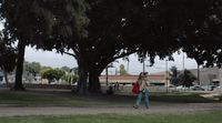 a woman walking down a street with a red bag