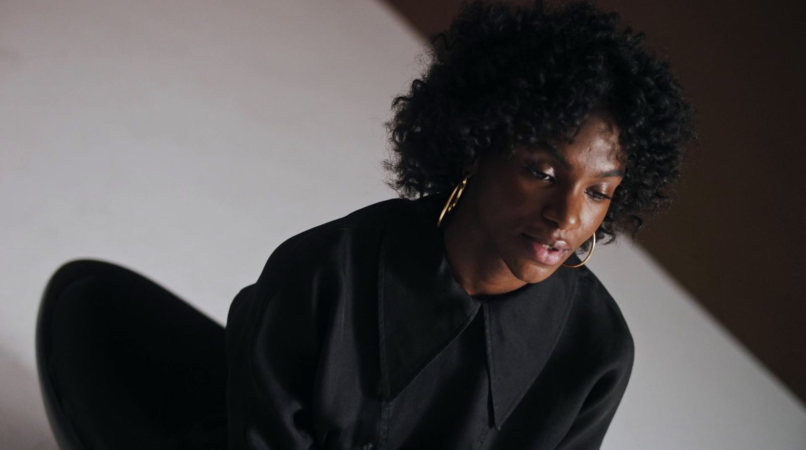 a woman in a black shirt and gold hoop earrings