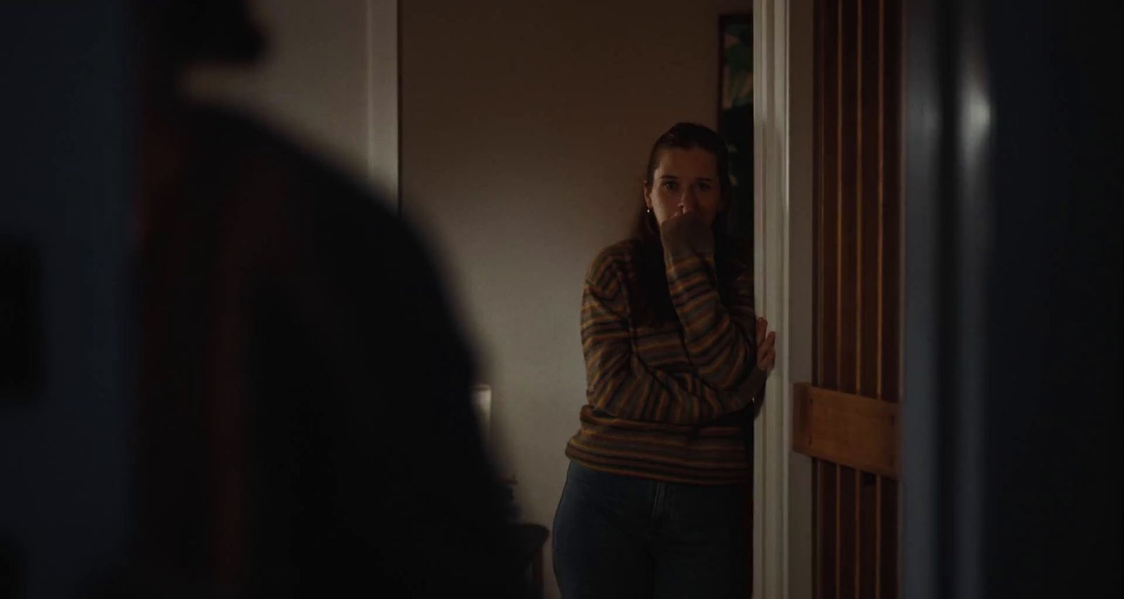 a woman standing in a doorway with her hand on her face