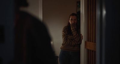 a woman standing in a doorway with her hand on her face