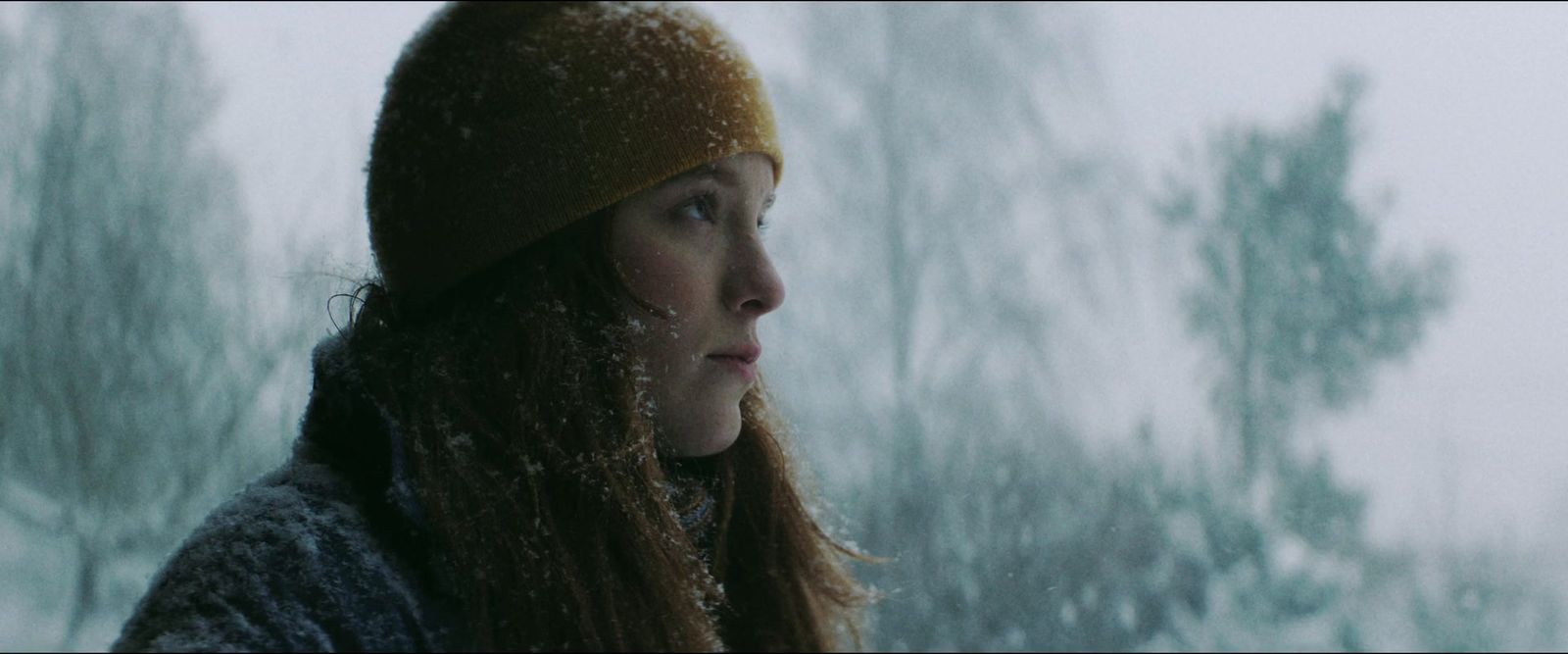 a woman standing outside in the snow wearing a hat