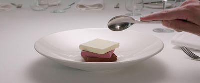 a person spooning a piece of cake on a plate