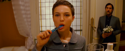 a woman brushing her teeth in front of a man