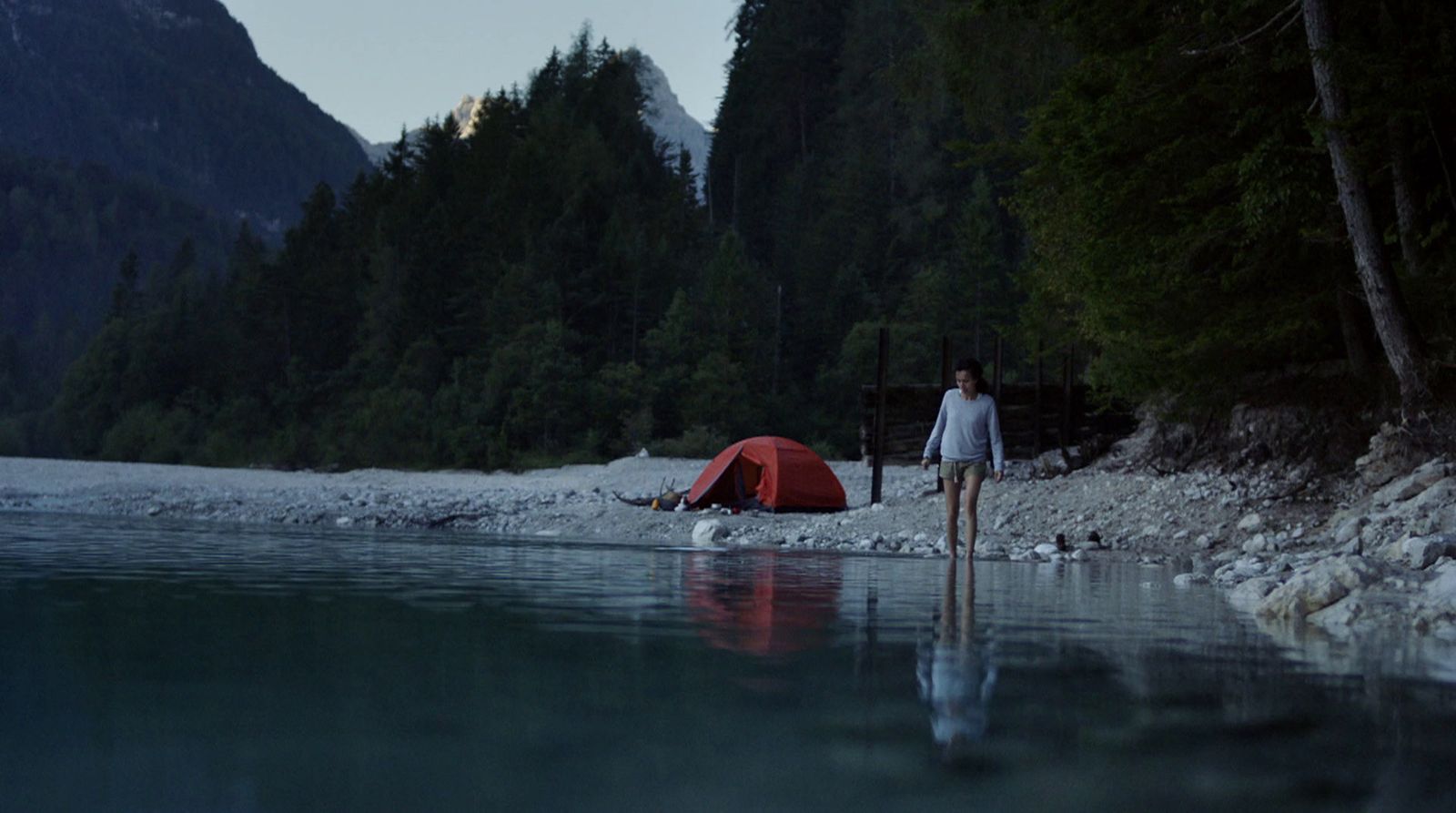 a woman standing next to a tent near a body of water