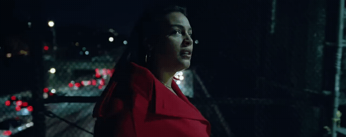 a woman in a red coat standing in the dark
