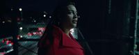 a woman in a red coat standing in the dark