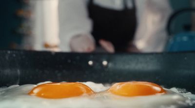 two eggs frying in a frying pan on a stove