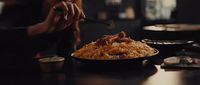 a woman eating a plate of food with chopsticks