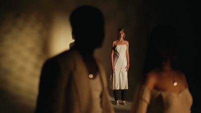 a woman in a white dress standing in front of a mirror