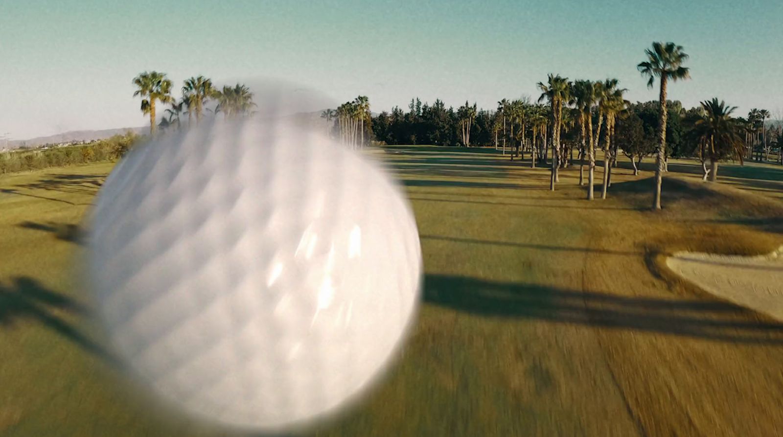 a golf ball flying over a golf course