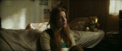 a woman with long red hair sitting on a bed