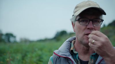 a man wearing a hat and glasses eating something