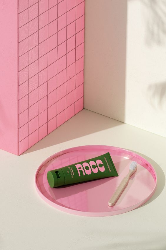 a toothbrush and tube of toothpaste on a pink tray