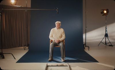 a man sitting on a chair in front of a blue backdrop