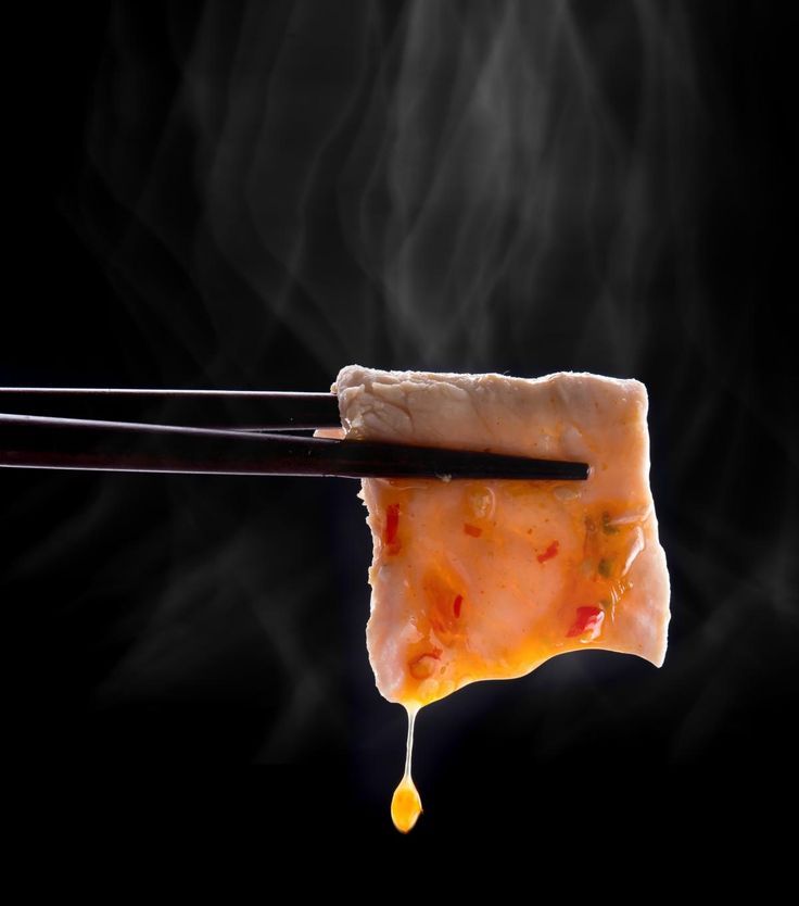 a piece of food is being held by chopsticks