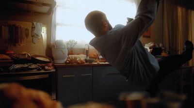 a man sitting in a kitchen next to a window