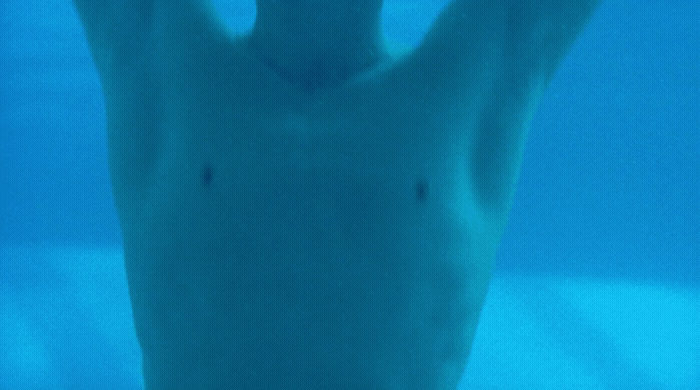 a man is swimming in the water with his hands up