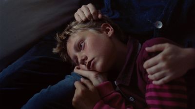 a young boy sitting on a couch with his hand on his chin