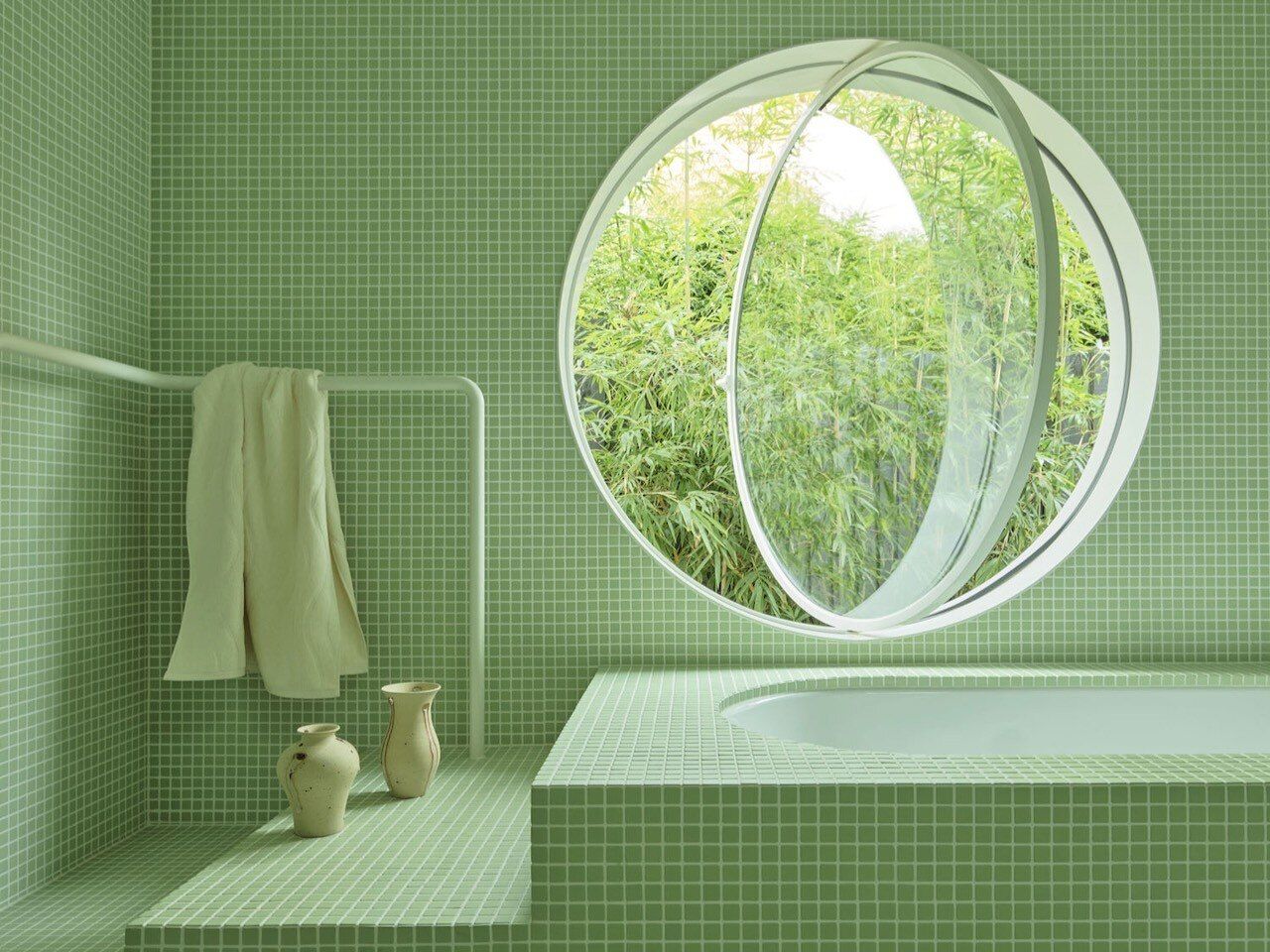 a green tiled bathroom with a round window