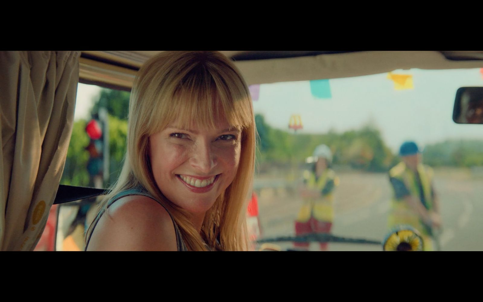 a woman sitting in a car with a group of people behind her