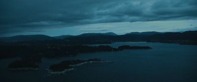 a body of water surrounded by mountains under a cloudy sky