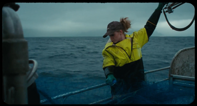 a woman in a yellow jacket on a boat in the ocean