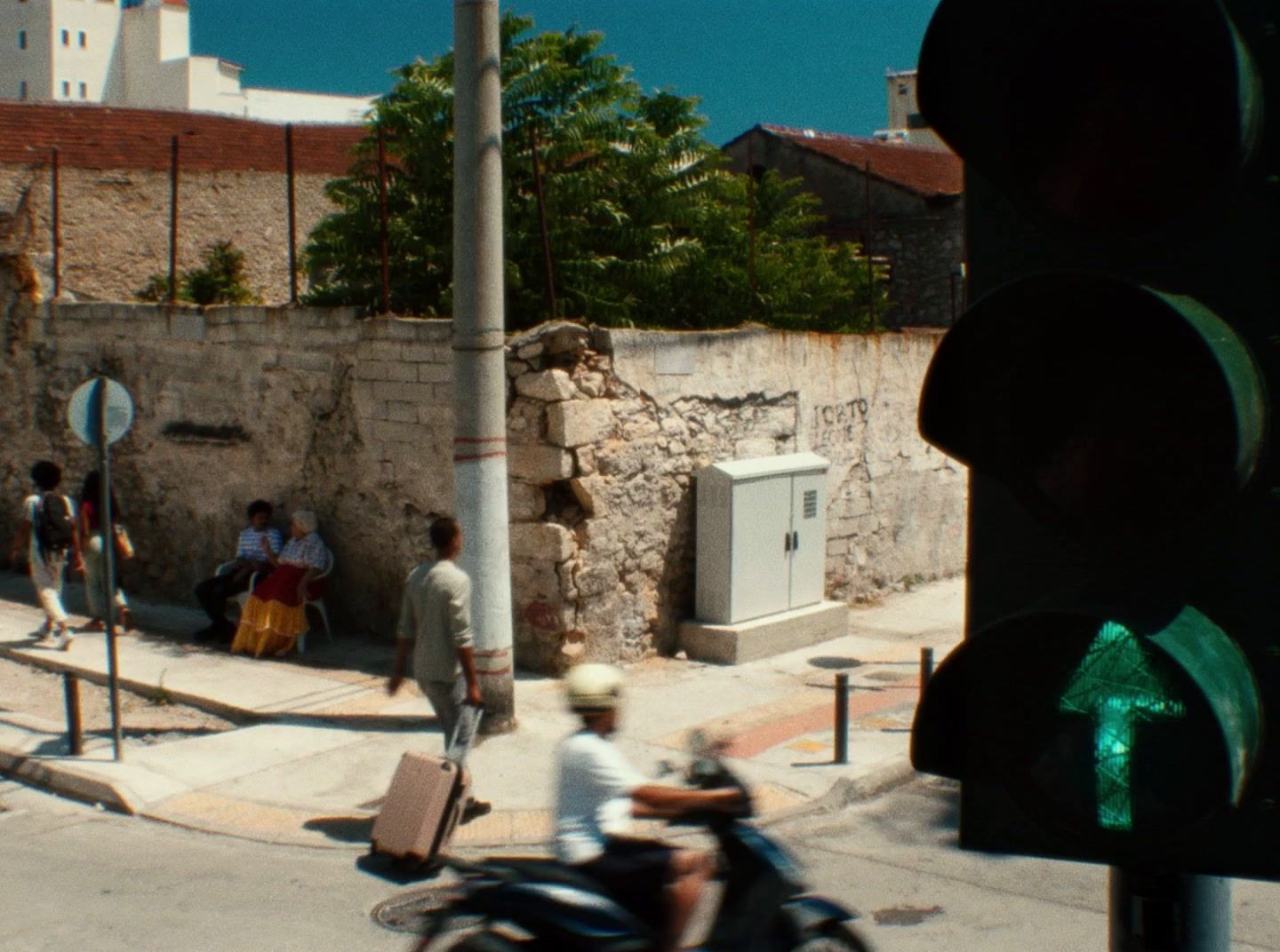 a man riding a motorcycle down a street next to a traffic light