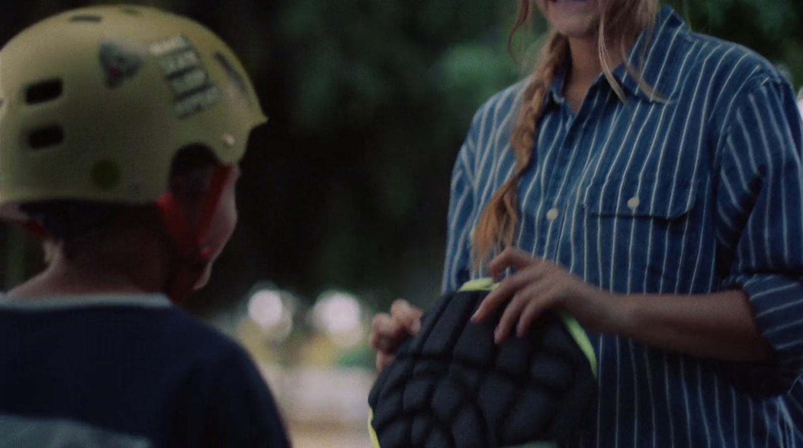 a woman holding a catchers mitt next to a young boy