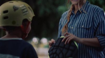 a woman holding a catchers mitt next to a young boy