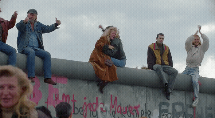 a group of people sitting on top of a cement wall