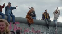 a group of people sitting on top of a cement wall