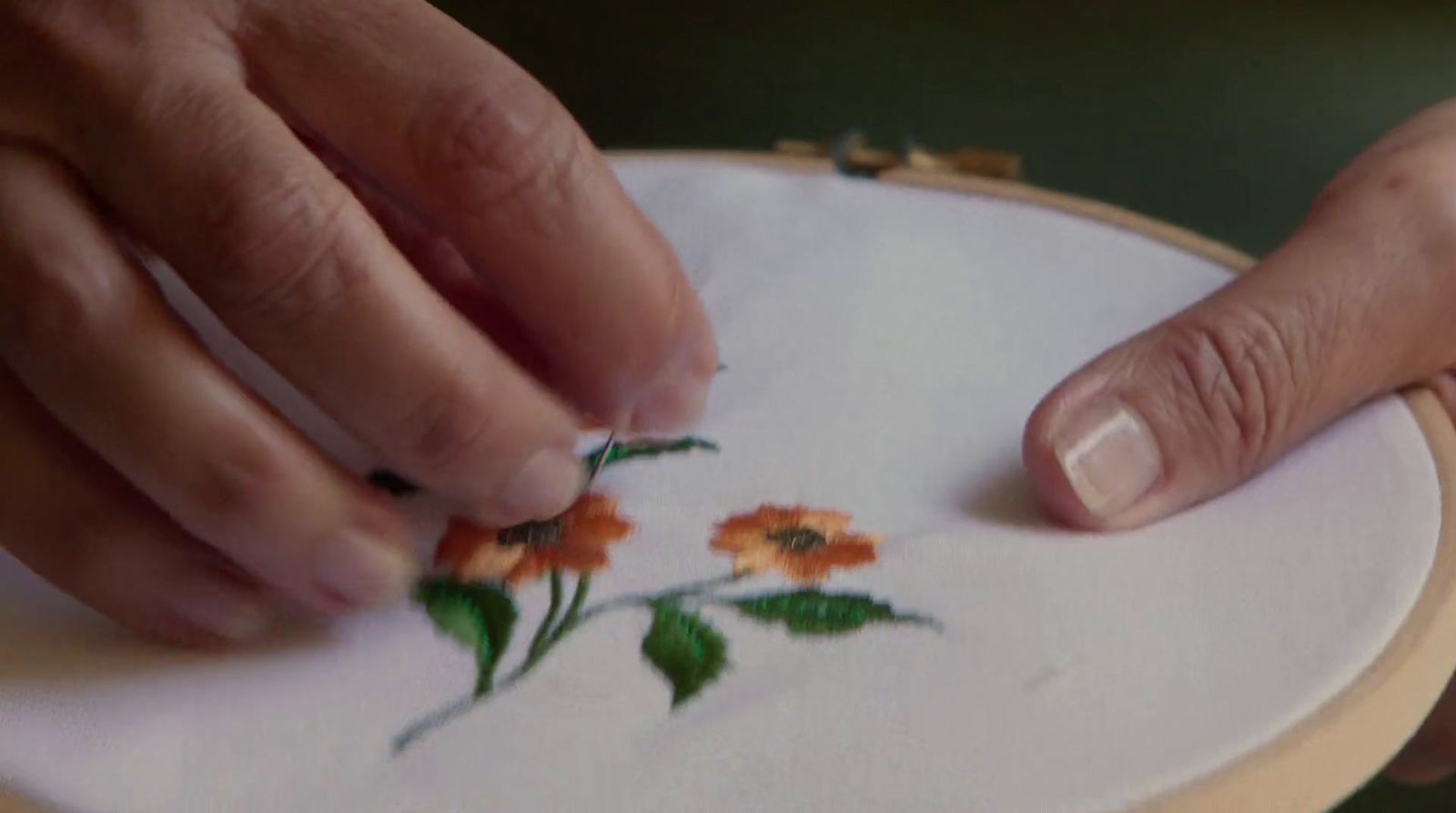 a close up of a person working on a embroidery project