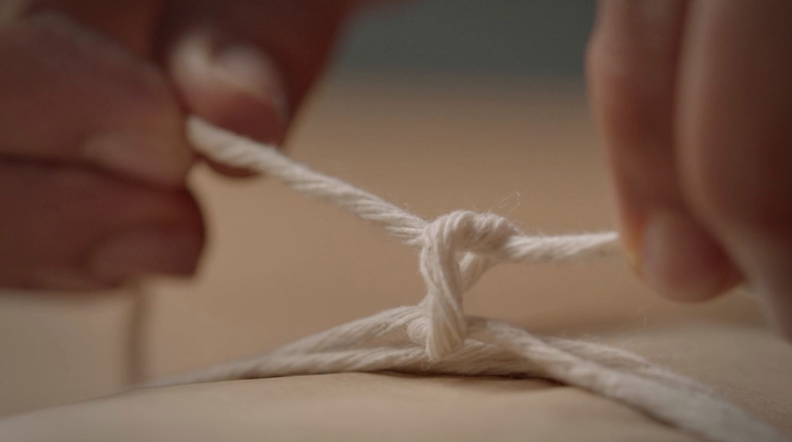 a person is tying a piece of white yarn