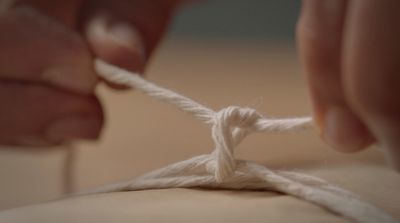 a person is tying a piece of white yarn