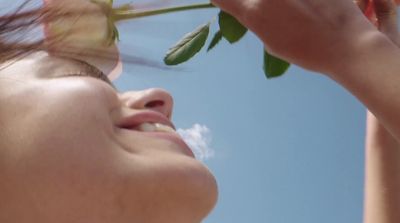 a woman holding a rose up to her face