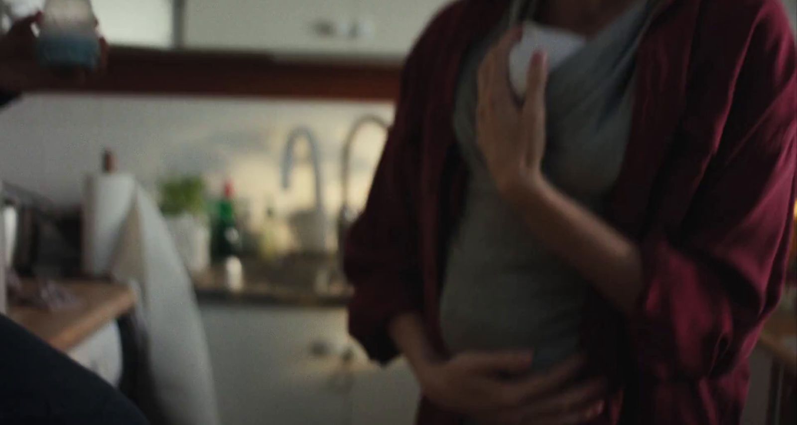 a woman standing in a kitchen holding her stomach