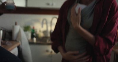 a woman standing in a kitchen holding her stomach