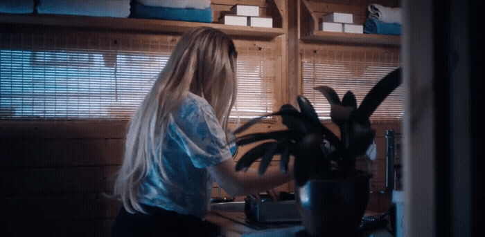 a woman standing in a kitchen next to a potted plant