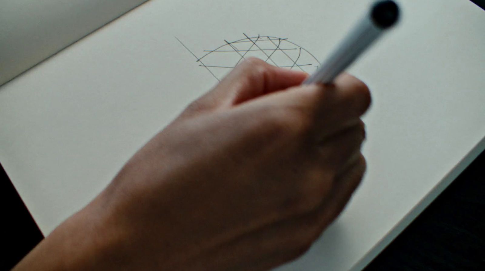 a person holding a pen and drawing a picture on a piece of paper