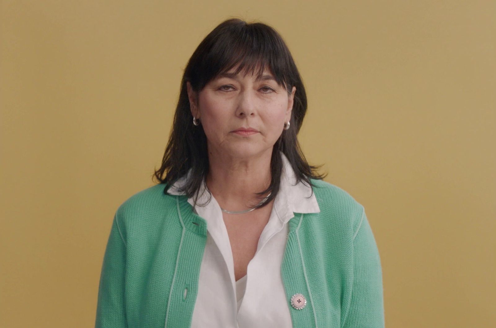 a woman standing in front of a yellow wall