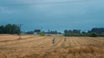 a couple of people riding bikes on top of a dry grass field